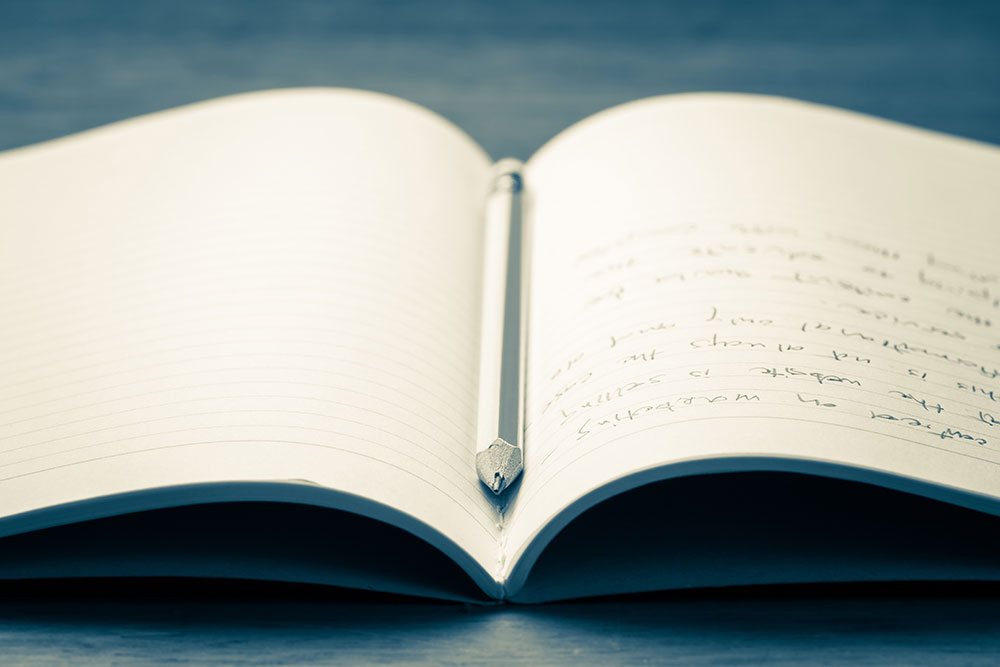 open book with handwriting and pencil on top